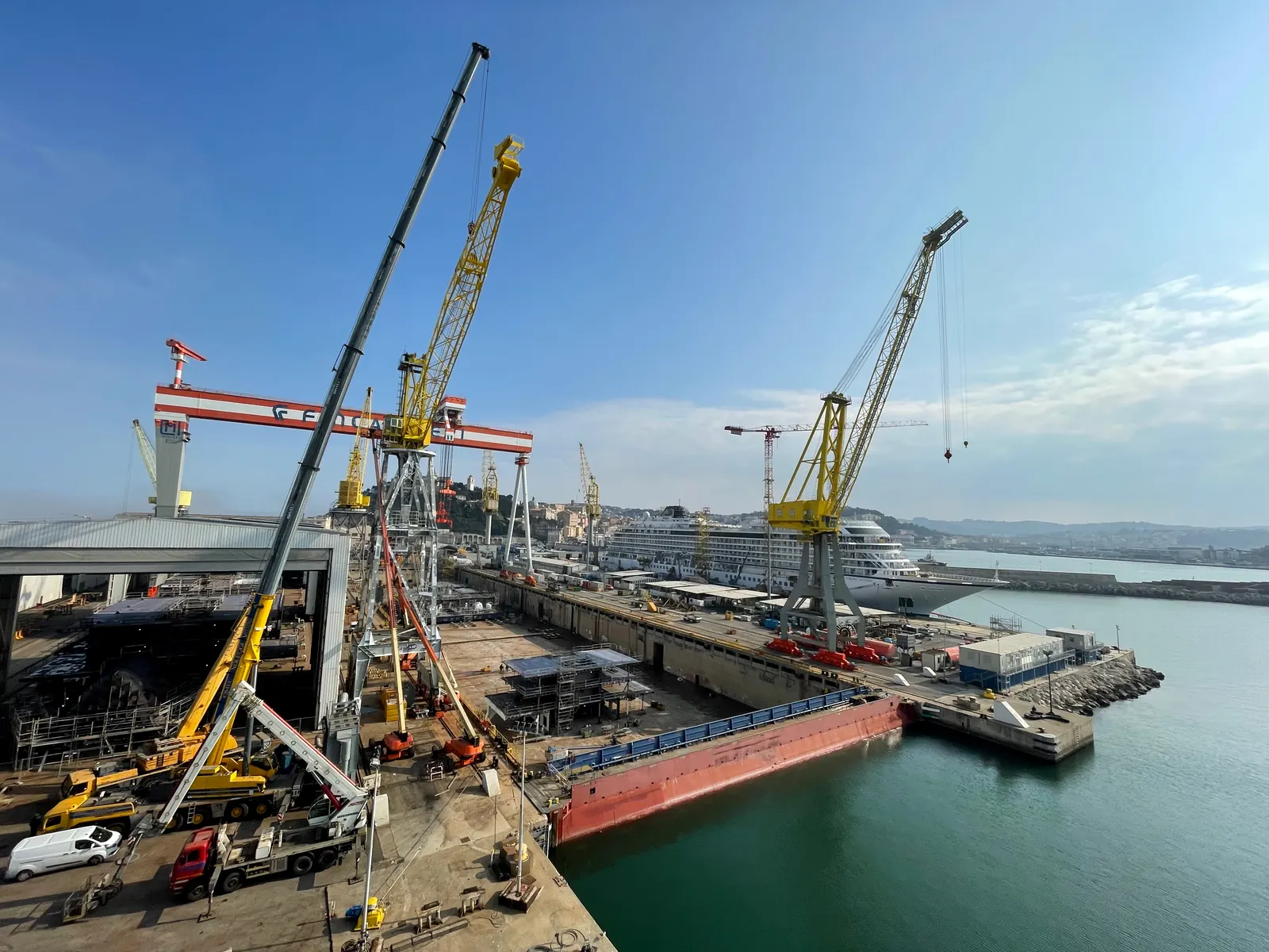 Grande cantiere navale con bacino, gru e nave in lavorazione